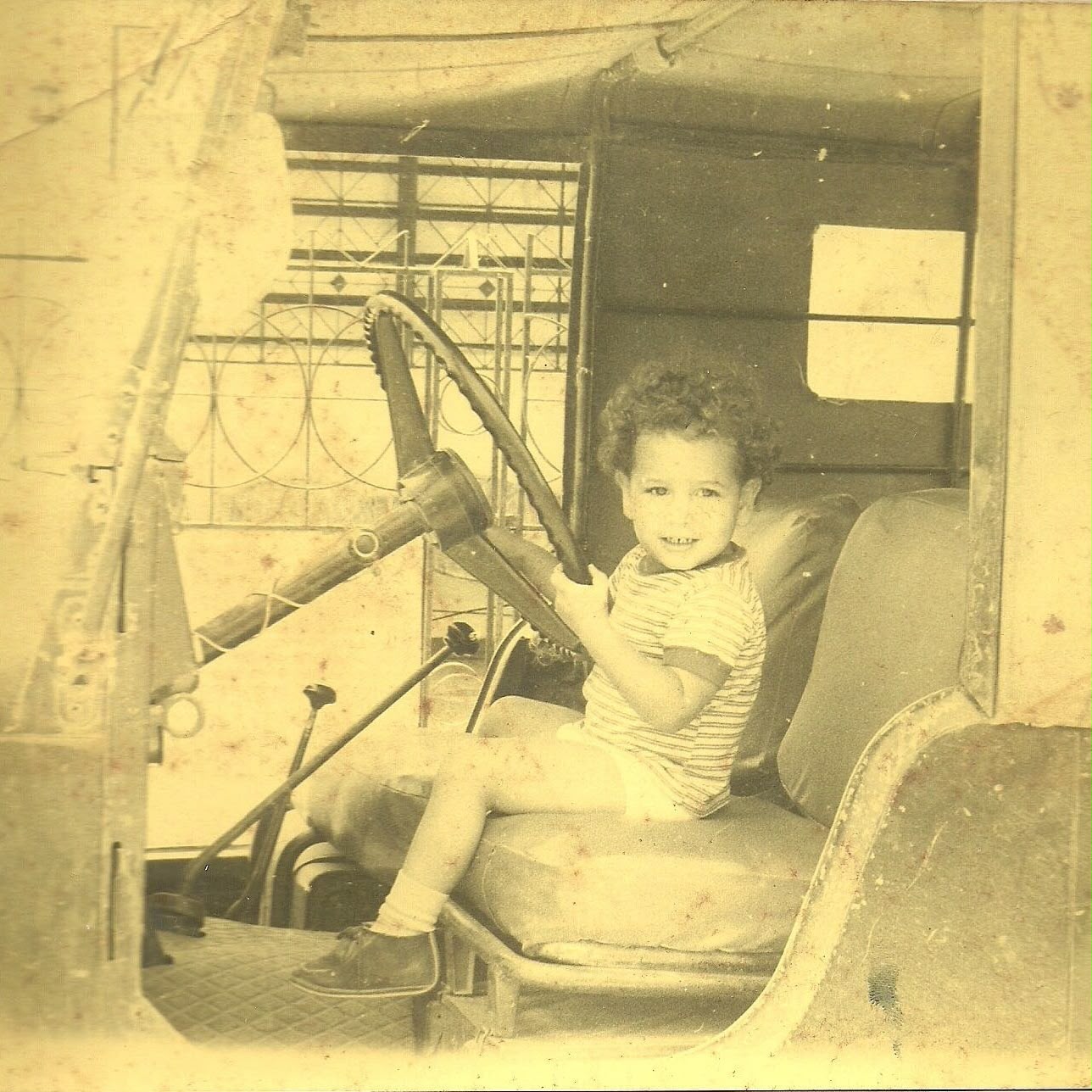 Young Ernesto sitting in an early Jeep, where his passion for vehicle care started